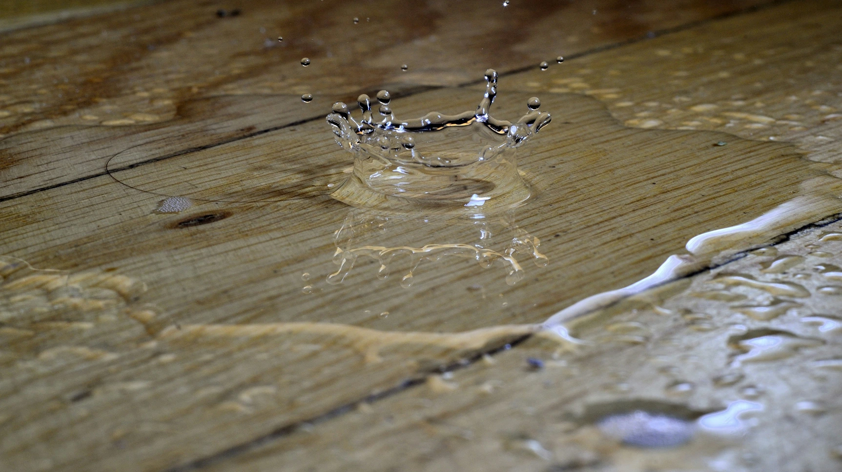 a photo of water leaking onto wooden floorboards into a puddle 